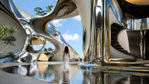 Eine einzelne Frau bewegt sich durch eine futuristische Architektur aus spiegelnden Metallflächen und organischen Bögen. Wasserbecken reflektieren Himmel, Gebäude und Figur zu einem komplexen Spiel aus Licht und Raum. Die glänzenden Oberflächen wirken gleichzeitig massiv und flüssig. Das Bild strahlt Ruhe, Eleganz und eine fast überirdische Klarheit aus.